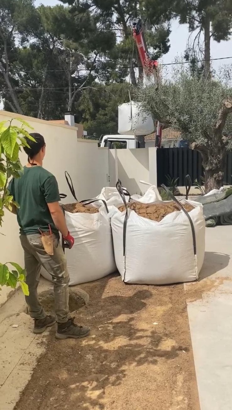 Trabajador de jardinería supervisando la entrega de materiales para el cuidado de plantas en un espacio al aire libre.