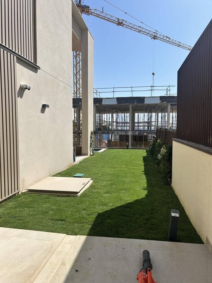 El mismo jardín después de la obra, con césped y seto perimetral