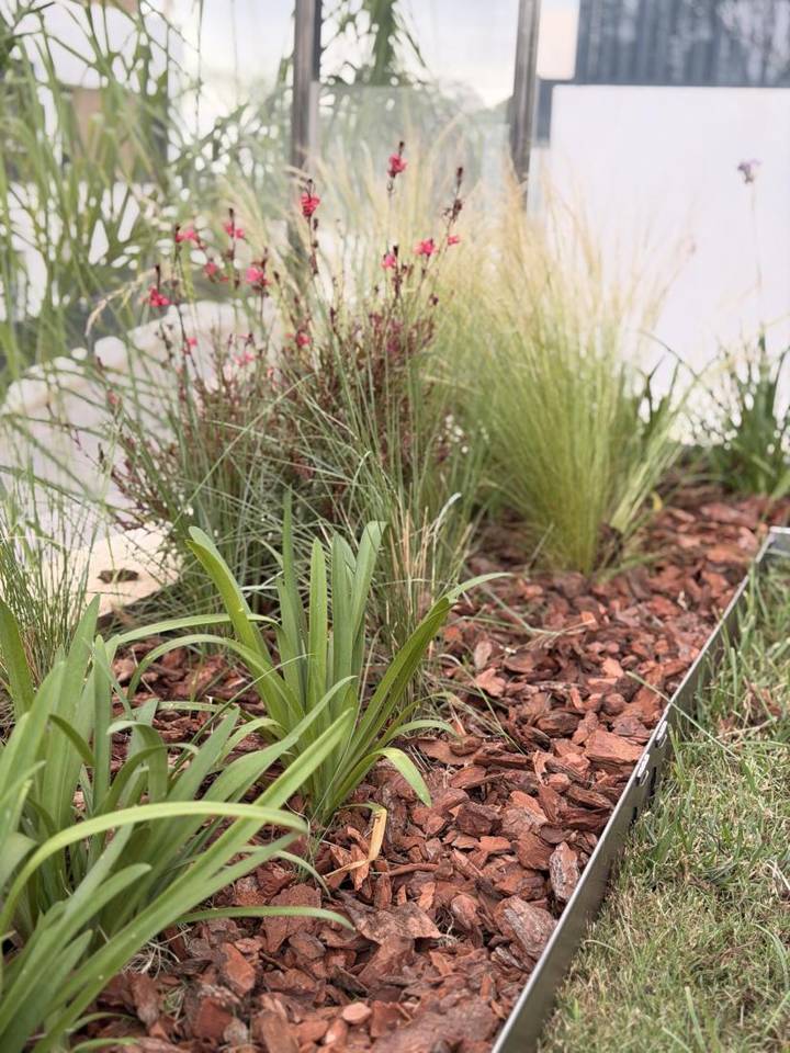 Macizo naturalista de stipa, gaura y agapanto con corteza de pino y borde de acero